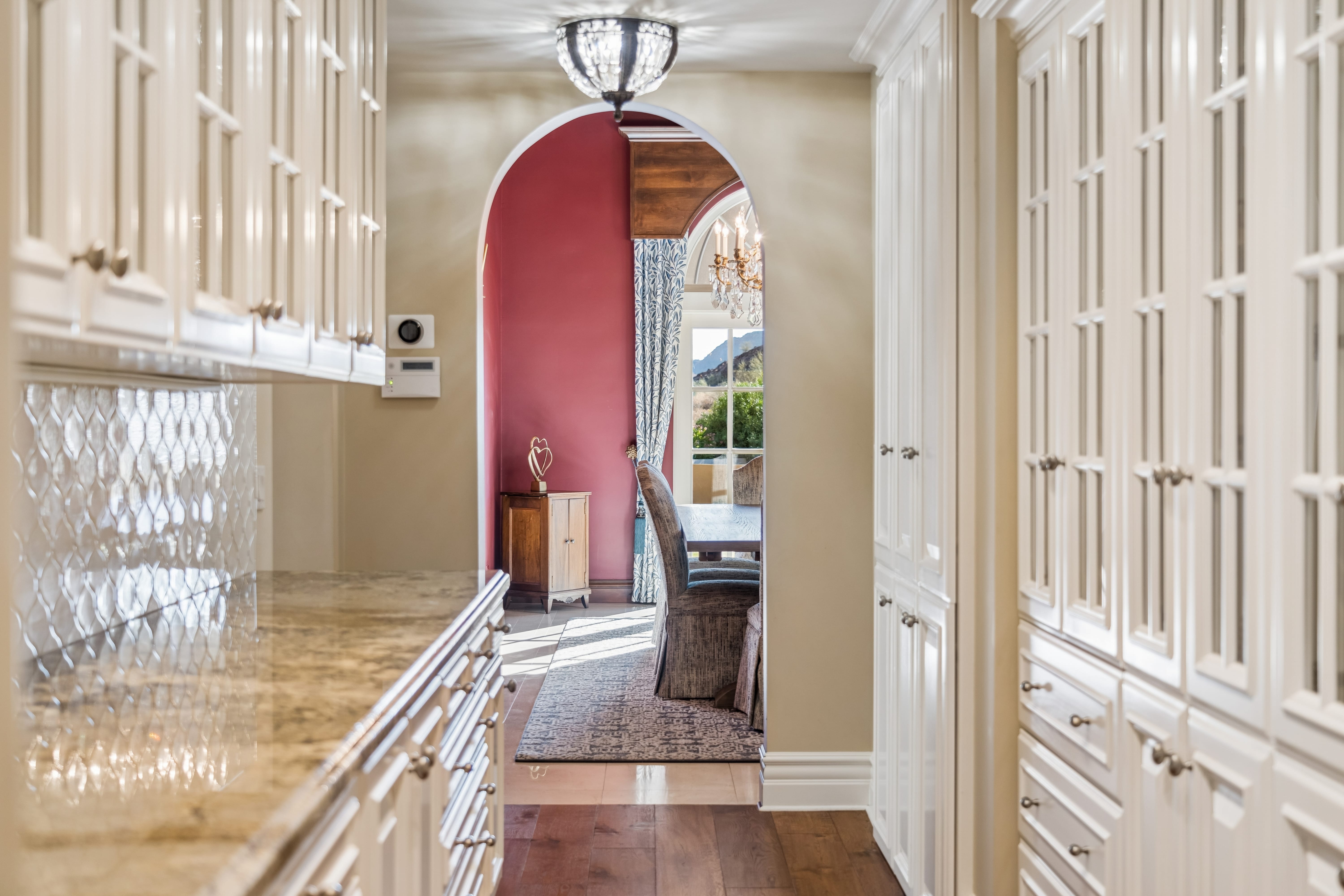 Butler's pantry with marble counters framing view to dining room