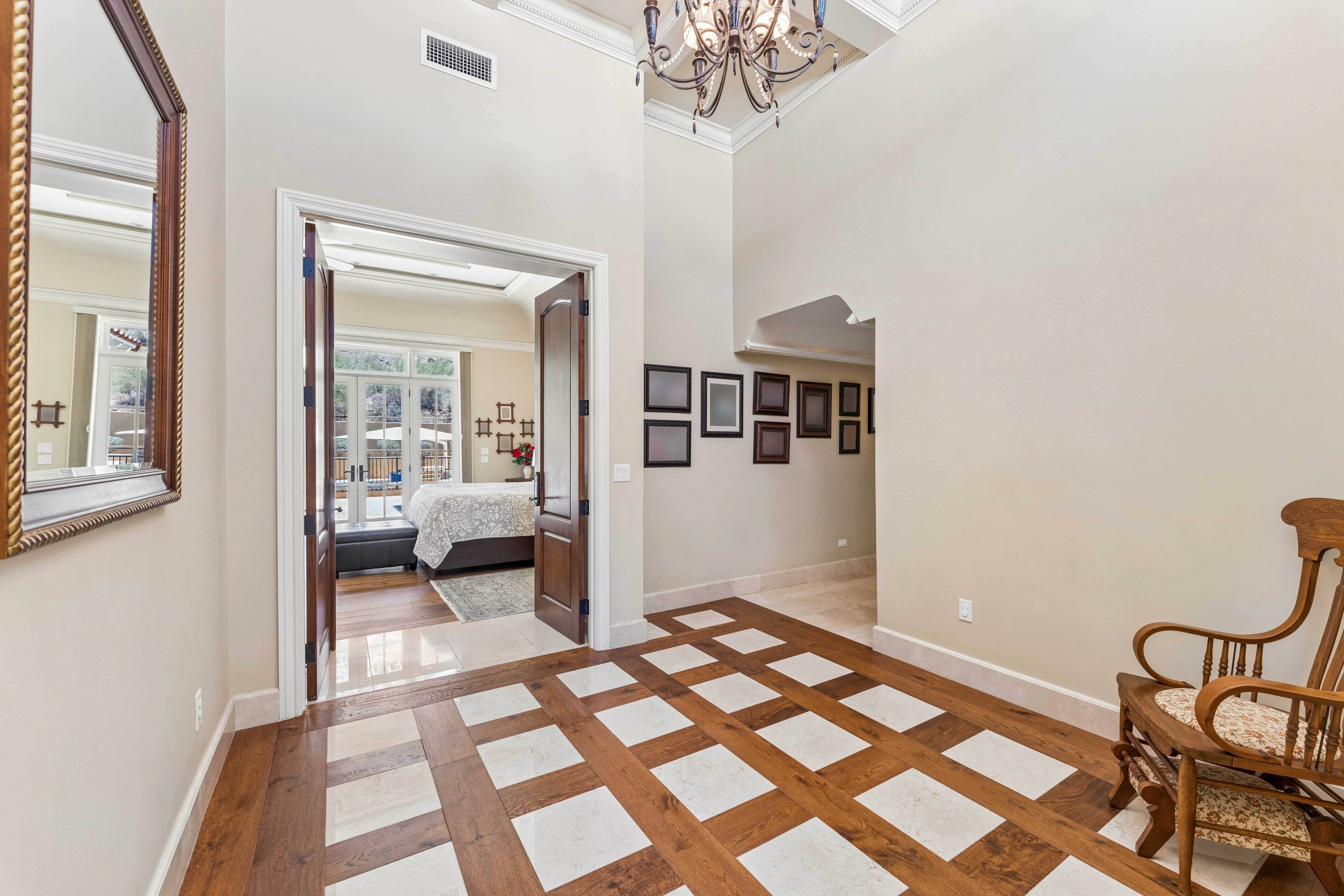 Primary suite foyer with chandelier and checkerboard inlay floor