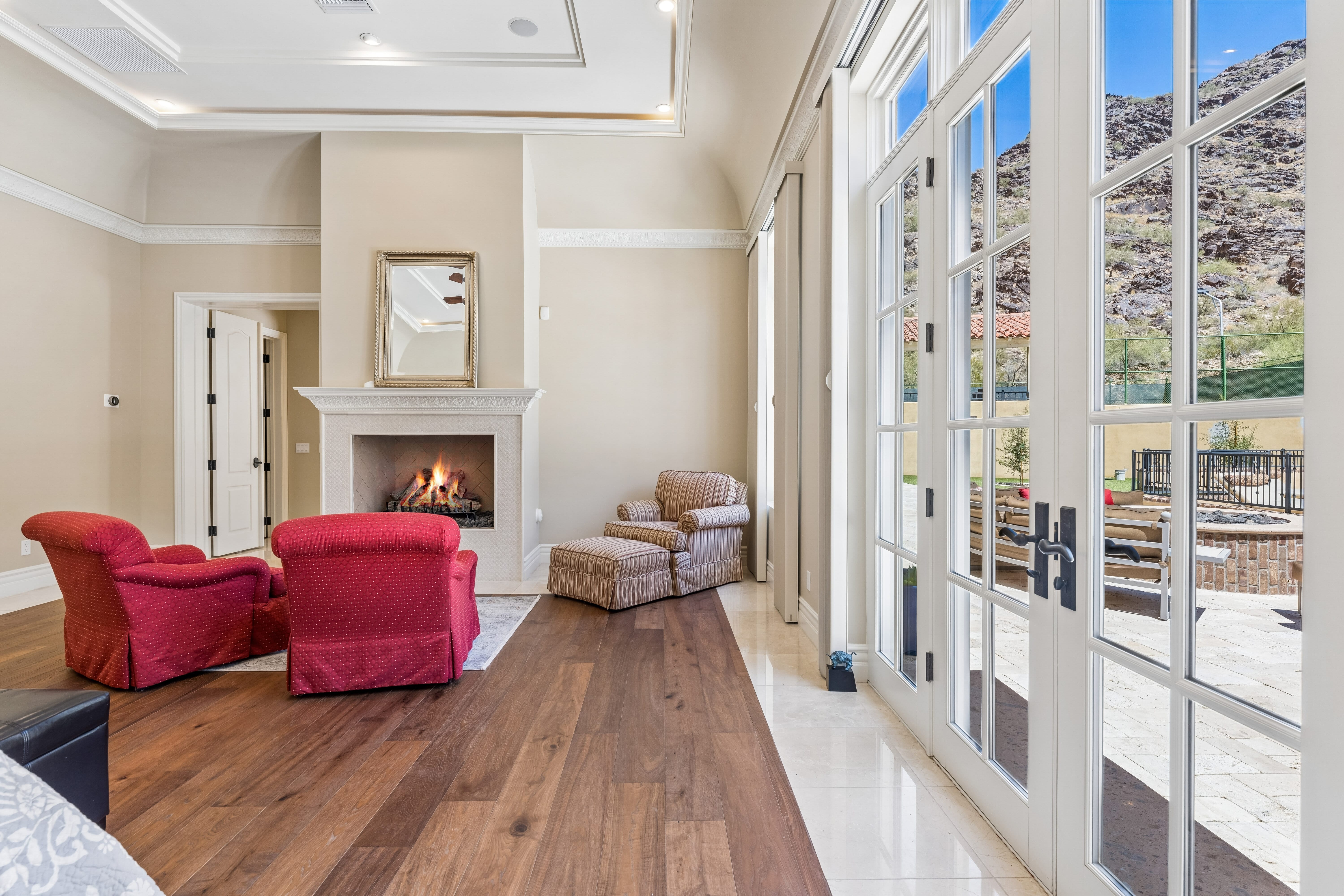 Primary suite sitting area with fireplace and French doors to pool