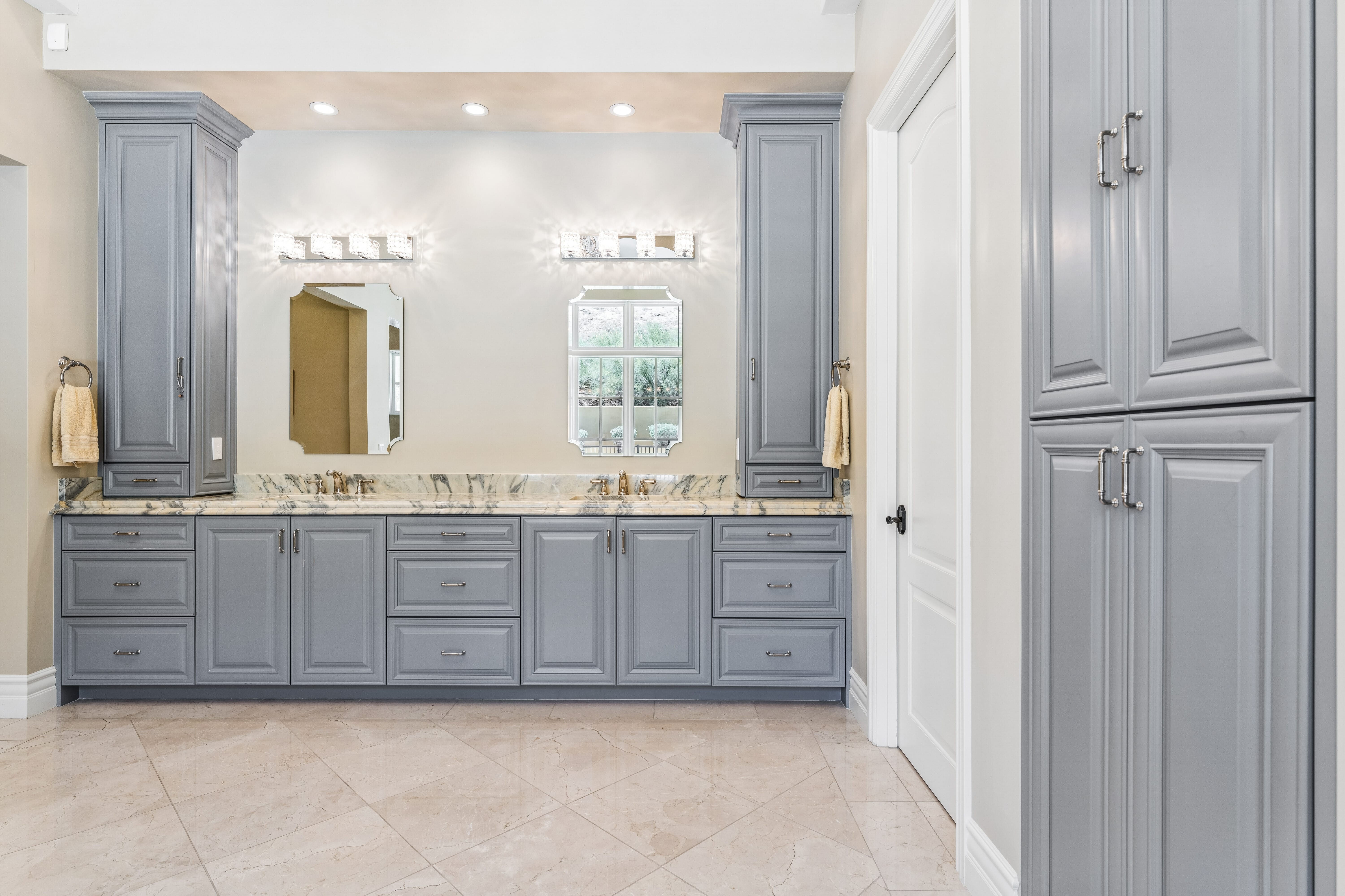 Primary bath dual vanity with grey cabinetry and marble counters