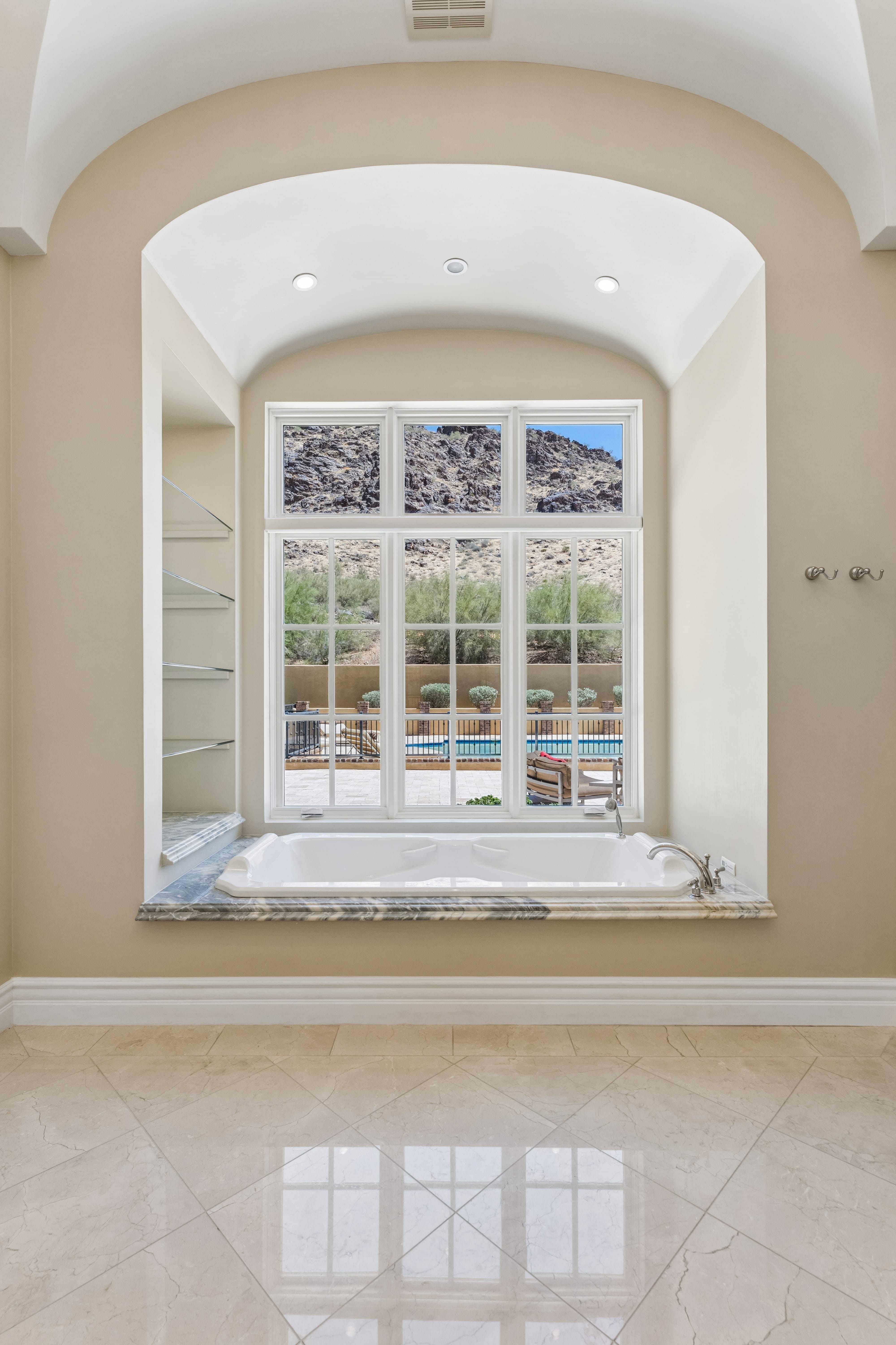 Primary bath tub alcove with arched vault and pool and canyon view