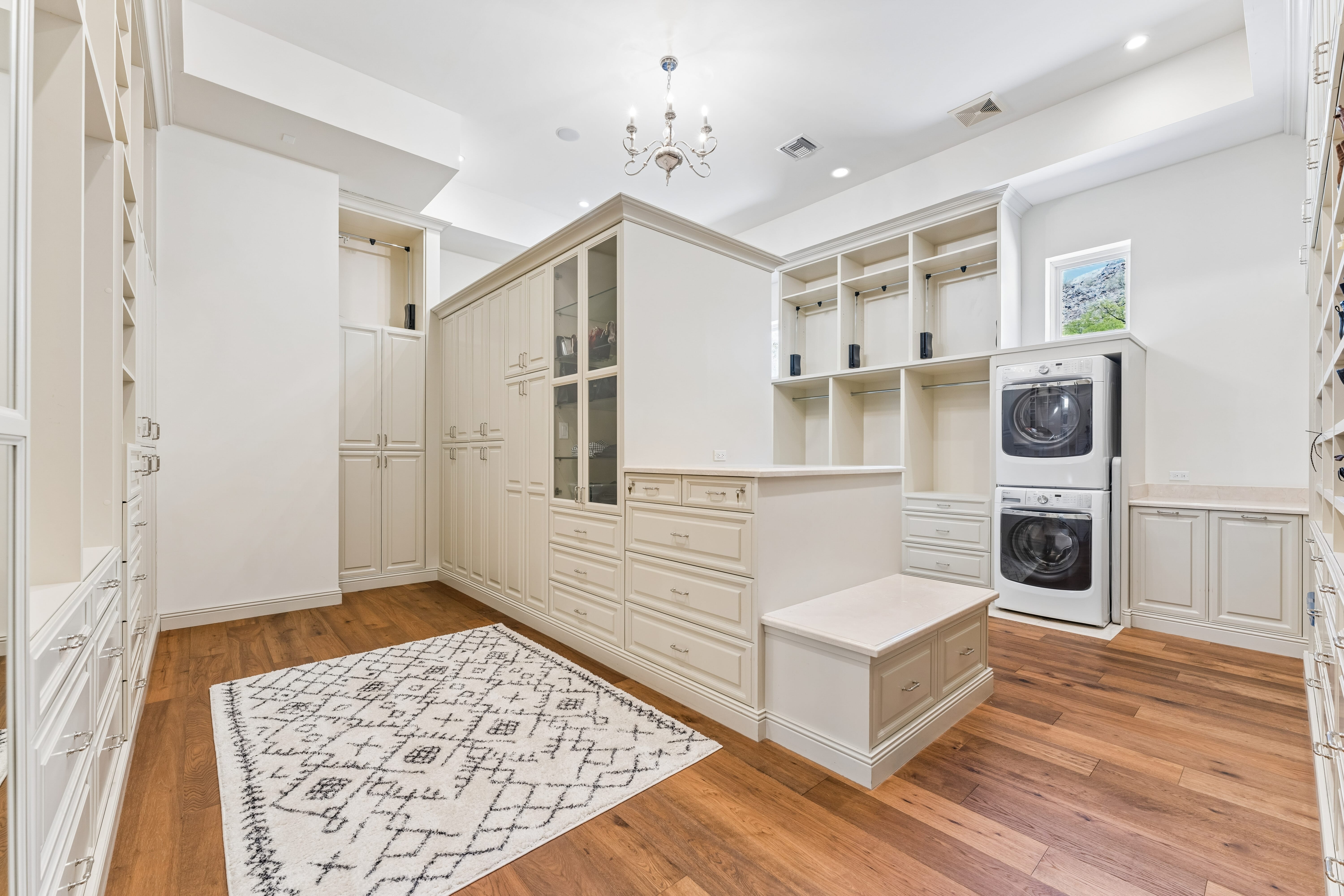 Primary closet with chandelier and custom cabinetry