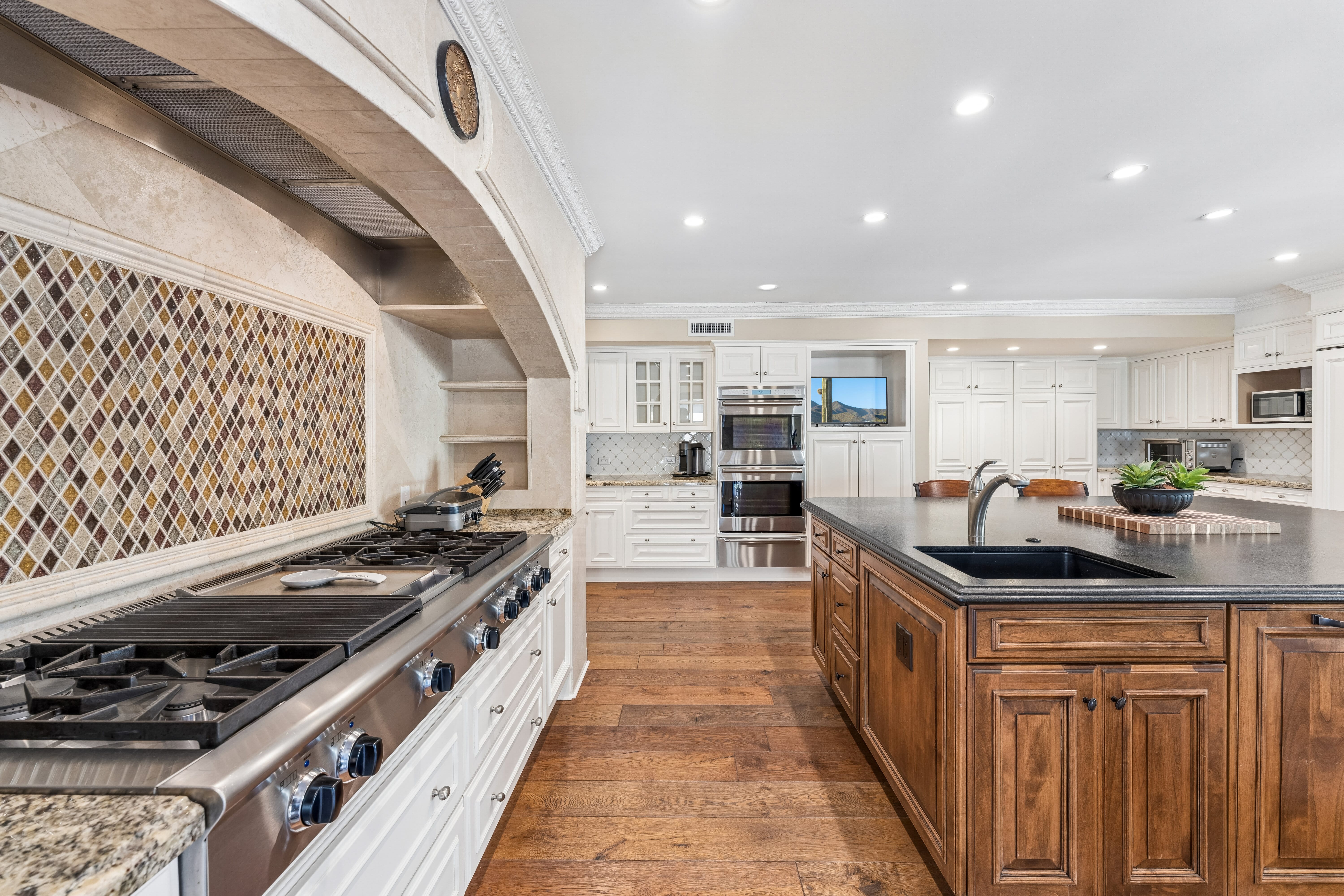 Kitchen range with arched stone hood and diamond mosaic backsplash