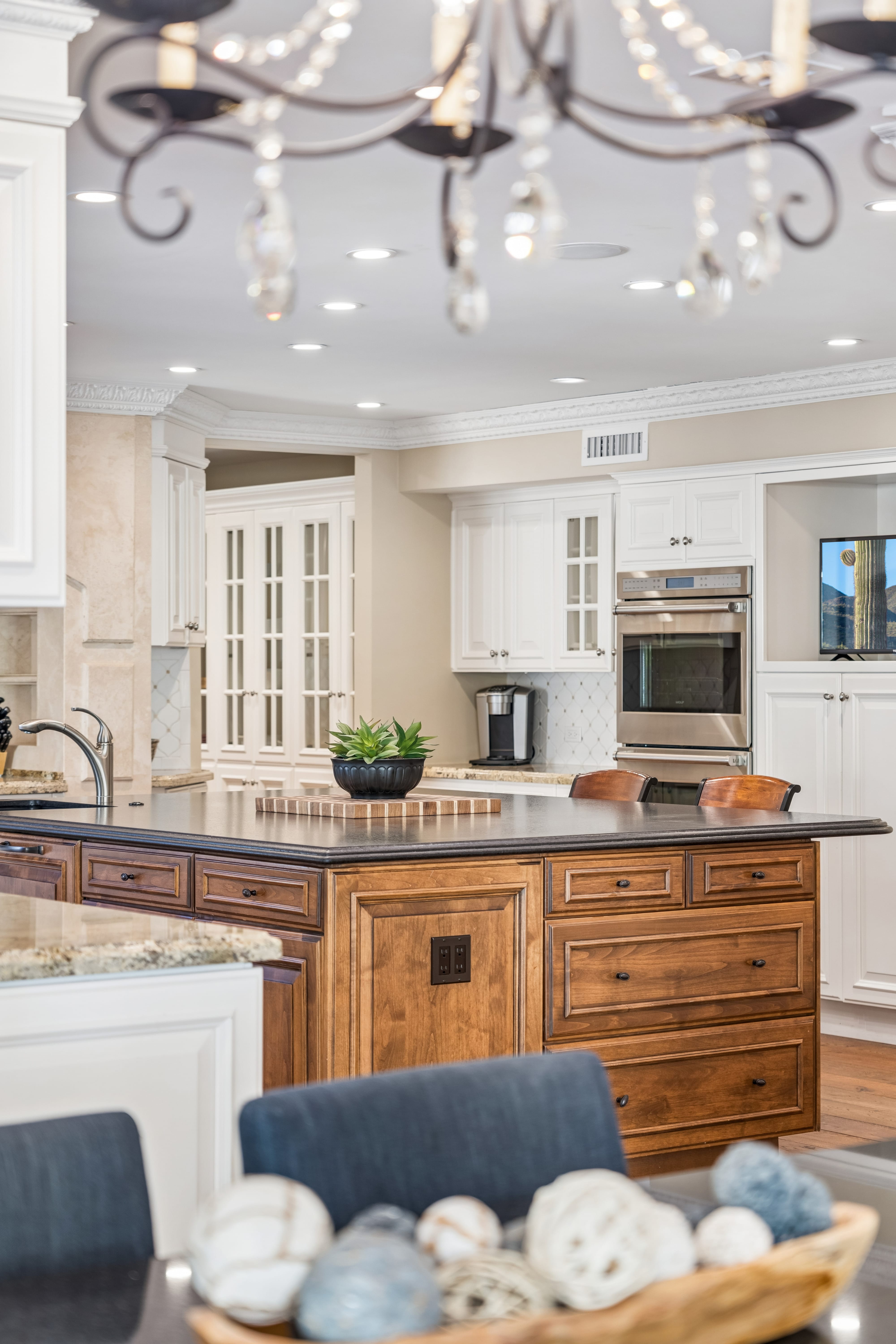 Kitchen island with wrought iron chandelier beyond