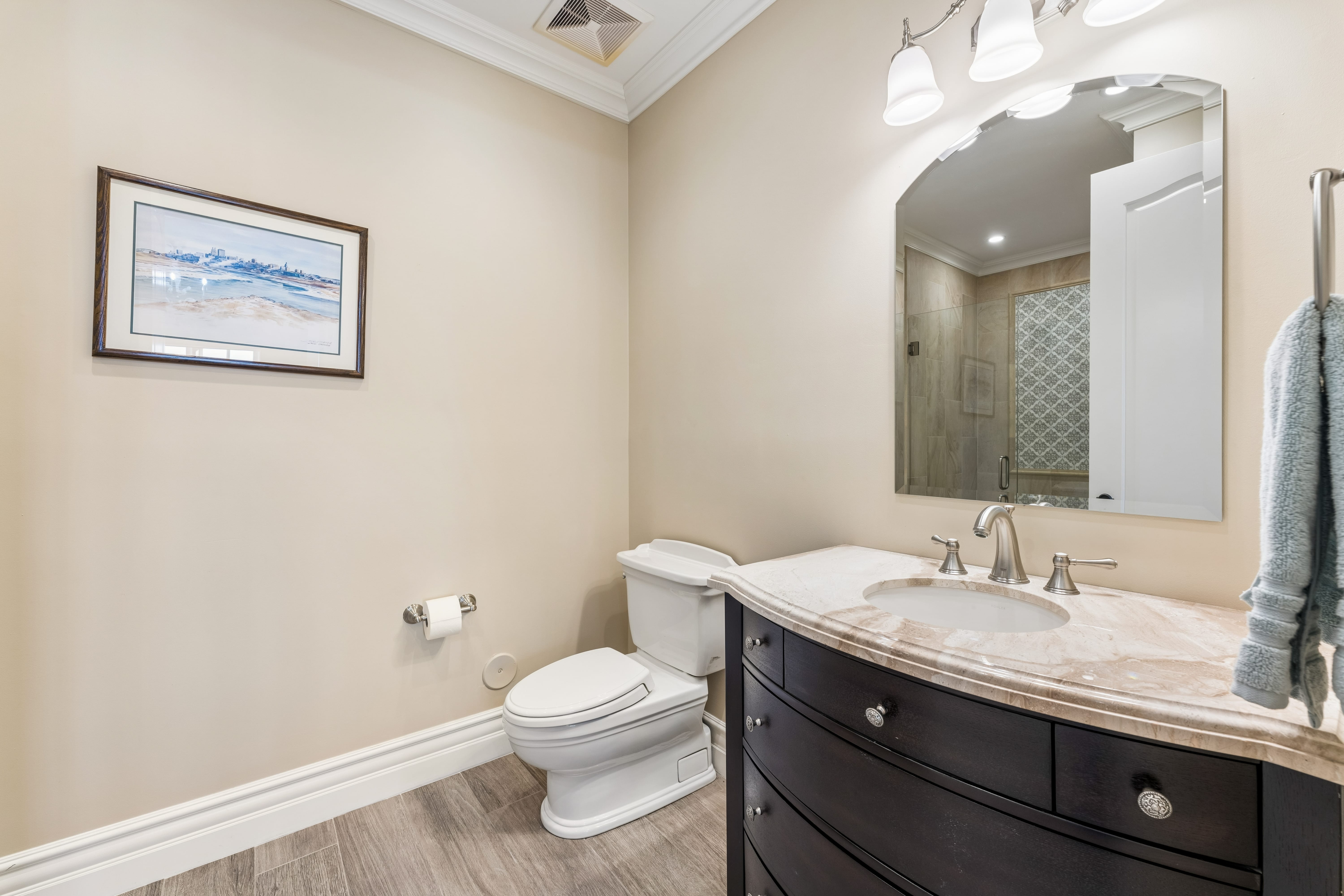 Full bath with curved espresso vanity and marble counter