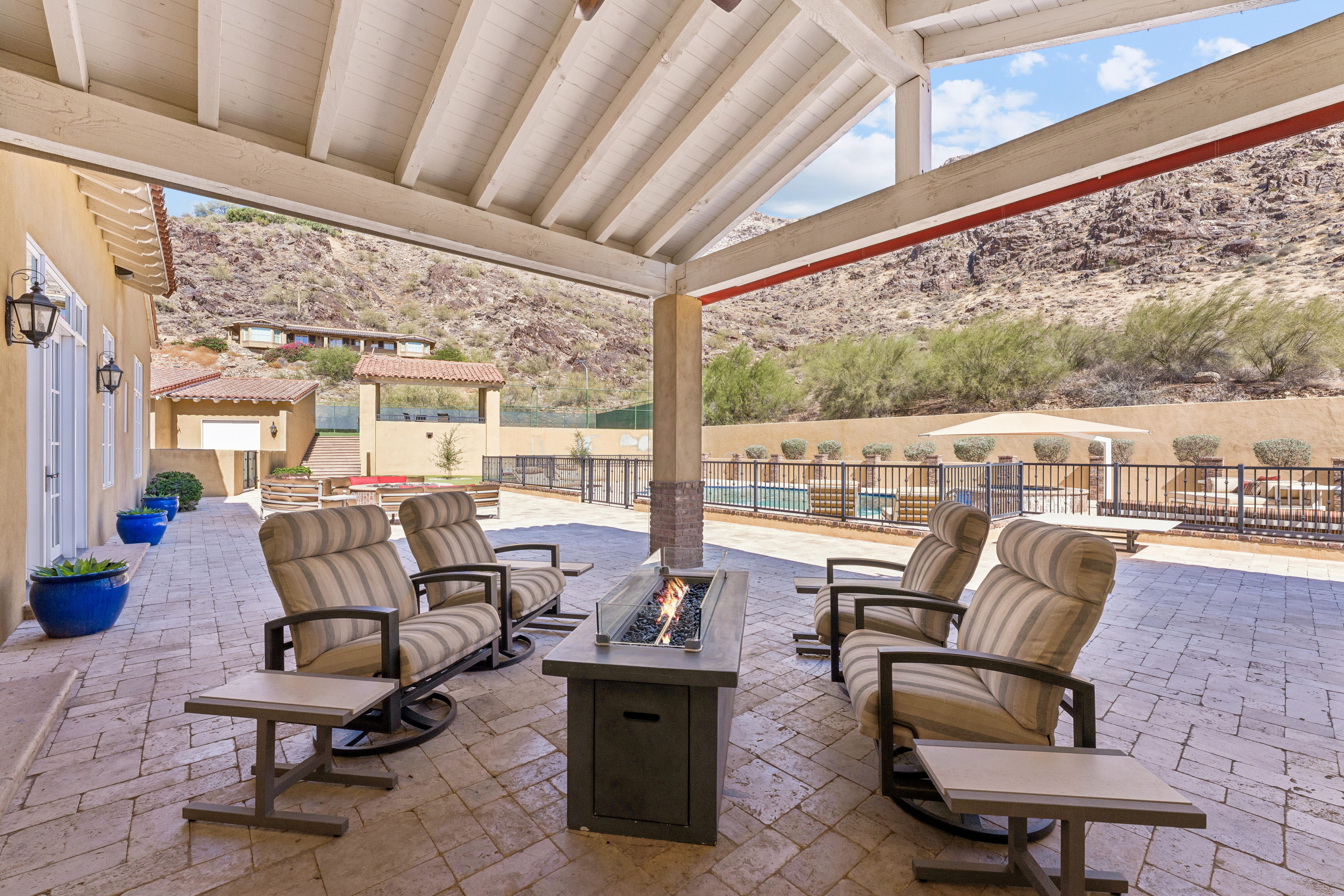 Covered loggia with fire table overlooking pool and tennis court