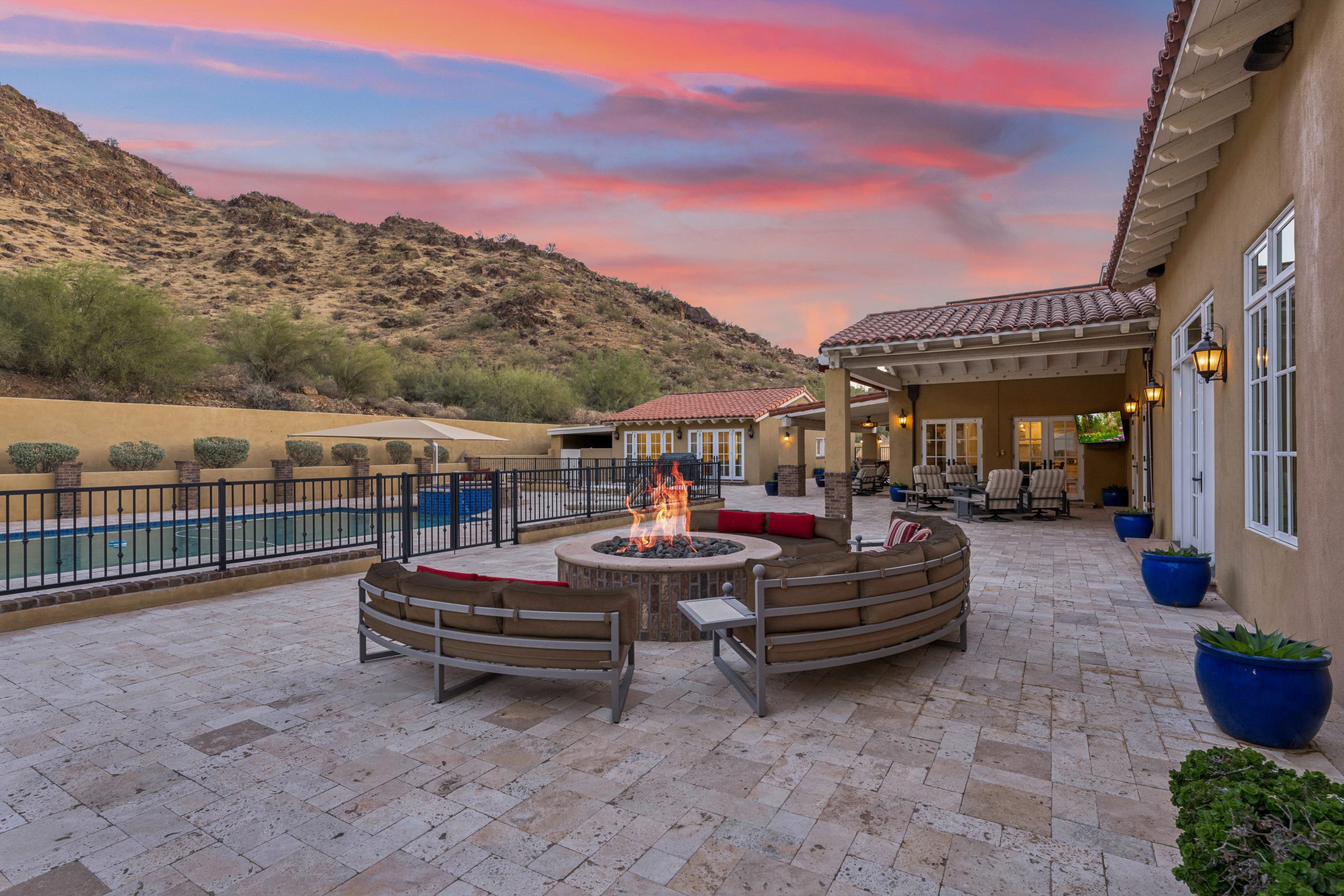 Fire pit at sunset with pool and loggia beyond